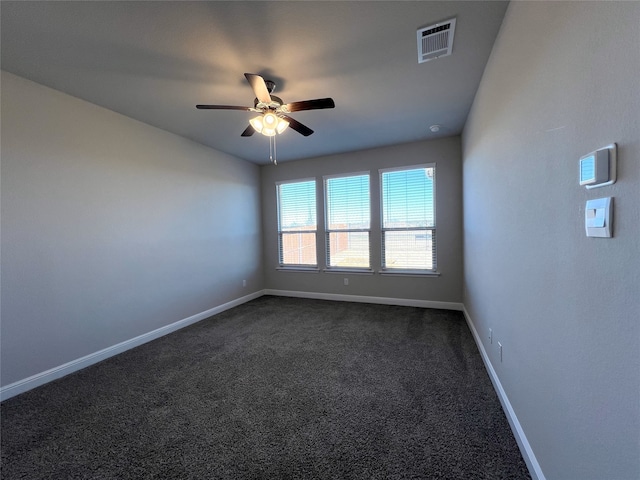 spare room featuring dark colored carpet and ceiling fan