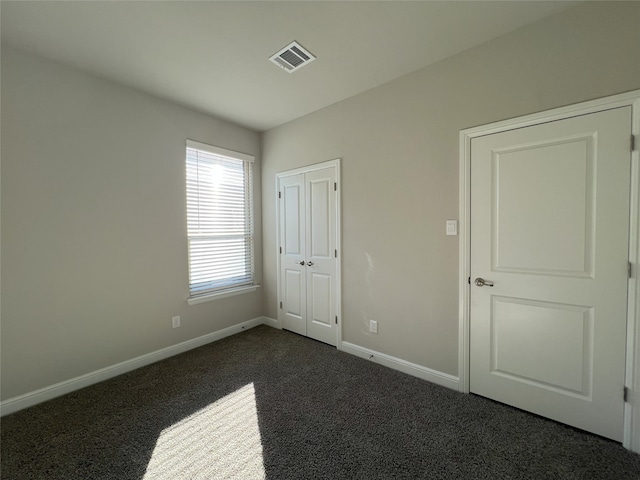 unfurnished bedroom featuring a closet and dark colored carpet