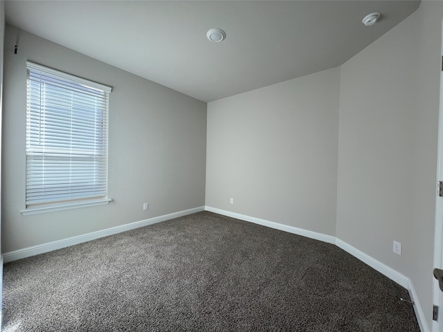 spare room with dark colored carpet