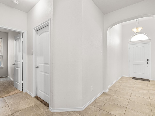 entryway featuring a healthy amount of sunlight, light tile patterned floors, baseboards, and arched walkways