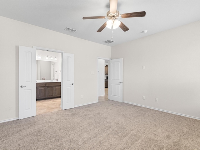 unfurnished bedroom featuring baseboards, visible vents, ensuite bathroom, and light colored carpet