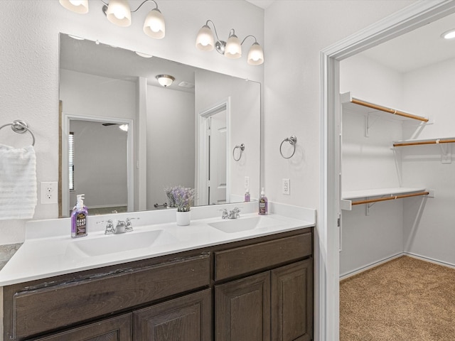 full bathroom with double vanity, a spacious closet, and a sink