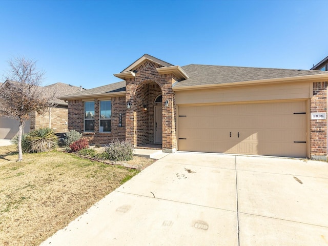 view of front facade with brick siding, a shingled roof, concrete driveway, a garage, and a front lawn