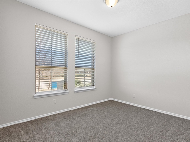 empty room with baseboards and dark colored carpet