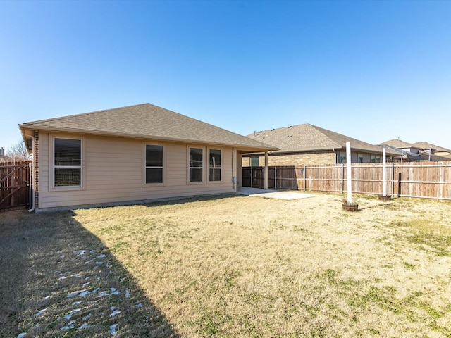 back of house with roof with shingles, a fenced backyard, a patio, and a lawn