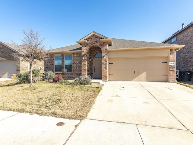 view of front of house with a garage, concrete driveway, brick siding, and a front lawn