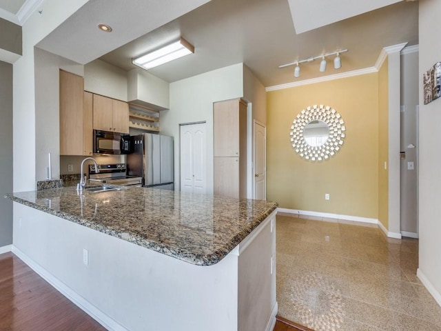 kitchen with appliances with stainless steel finishes, dark stone countertops, and kitchen peninsula