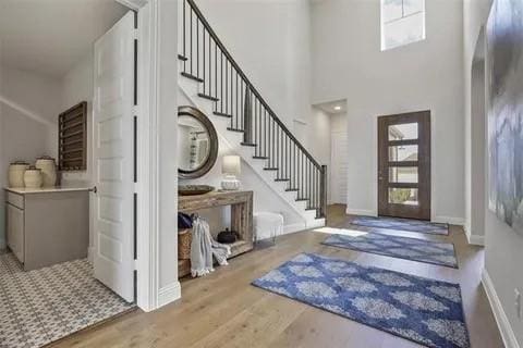 foyer entrance with french doors, a towering ceiling, and light hardwood / wood-style flooring