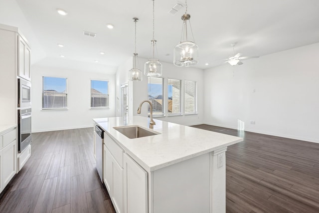 kitchen with sink, white cabinets, hanging light fixtures, stainless steel appliances, and a center island with sink