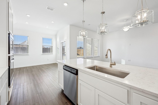 kitchen with stainless steel appliances, white cabinetry, sink, and light stone counters