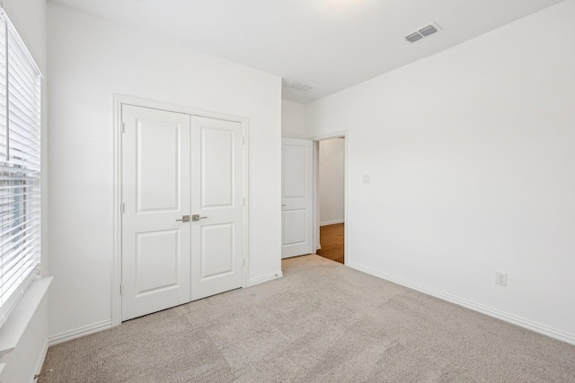 unfurnished bedroom with light carpet and a closet