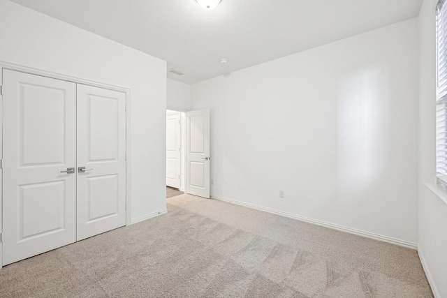 unfurnished bedroom with light colored carpet and a closet