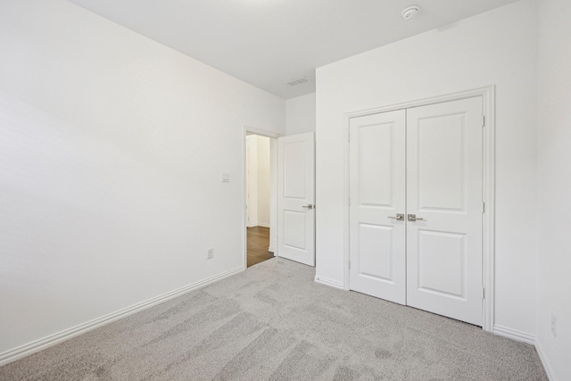 unfurnished bedroom with light carpet and a closet