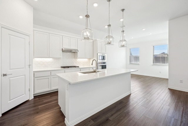 kitchen with white cabinetry, stainless steel appliances, an island with sink, and hanging light fixtures