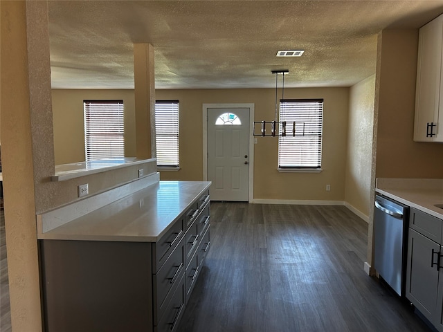 kitchen featuring pendant lighting, a textured ceiling, dark hardwood / wood-style floors, gray cabinets, and stainless steel dishwasher