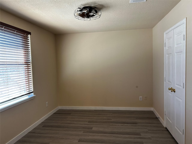 unfurnished room with a textured ceiling and dark hardwood / wood-style flooring