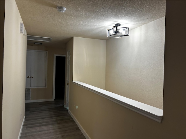 hallway with dark wood-type flooring and a textured ceiling