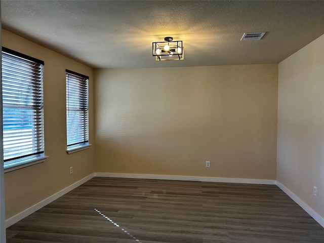 unfurnished room featuring dark hardwood / wood-style floors, a chandelier, and a textured ceiling