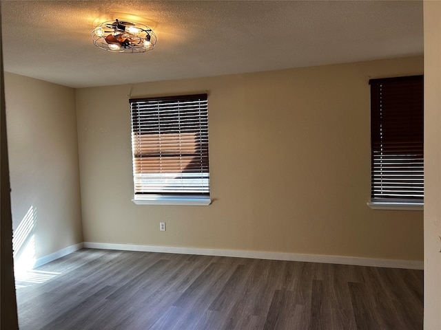 empty room with dark hardwood / wood-style floors and a textured ceiling