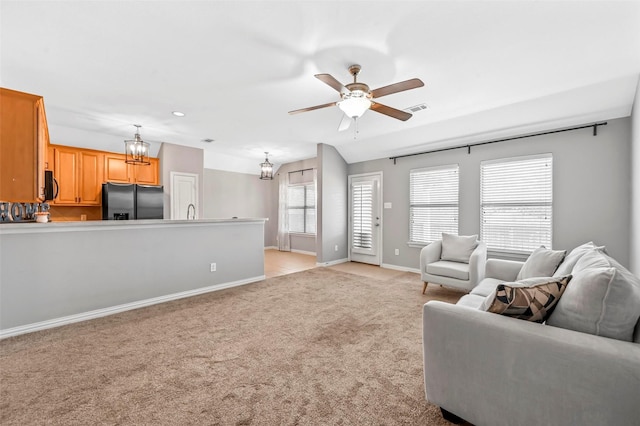 carpeted living room featuring ceiling fan with notable chandelier