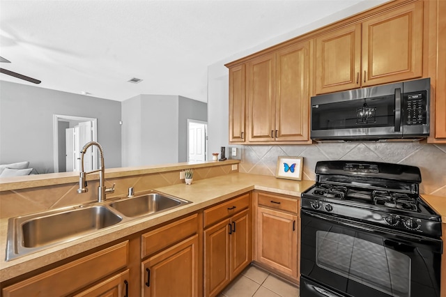 kitchen featuring sink, backsplash, kitchen peninsula, black gas range, and light tile patterned floors