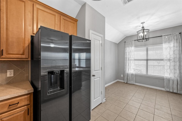 kitchen featuring vaulted ceiling, decorative light fixtures, backsplash, stainless steel fridge, and light tile patterned flooring