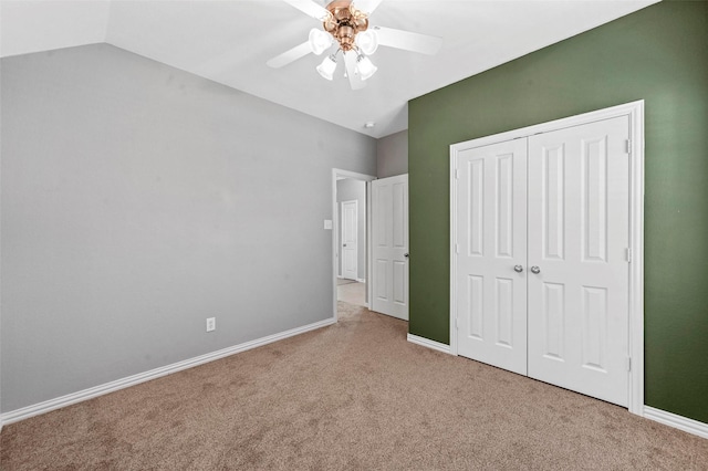 unfurnished bedroom featuring lofted ceiling, ceiling fan, a closet, and light colored carpet