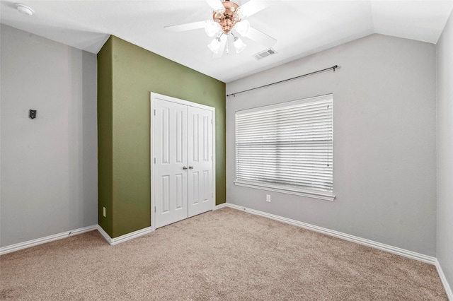 unfurnished bedroom with vaulted ceiling, ceiling fan, a closet, and light carpet