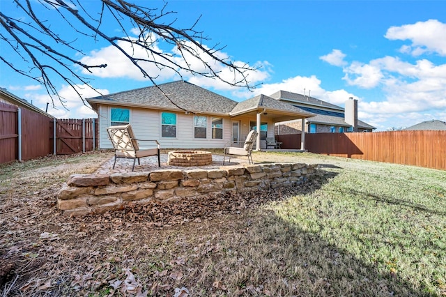 rear view of property with a yard, a fire pit, and a patio