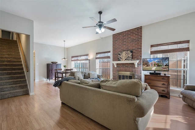 living room featuring a brick fireplace, light hardwood / wood-style flooring, and ceiling fan