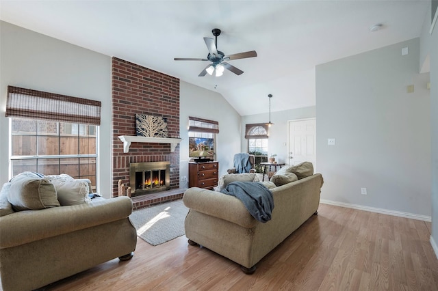 living room with ceiling fan, light hardwood / wood-style flooring, lofted ceiling, and a fireplace