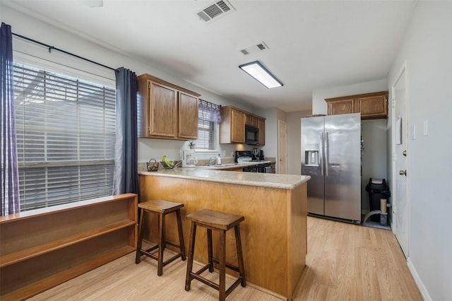 kitchen with kitchen peninsula, sink, light hardwood / wood-style flooring, stainless steel fridge with ice dispenser, and range with gas stovetop