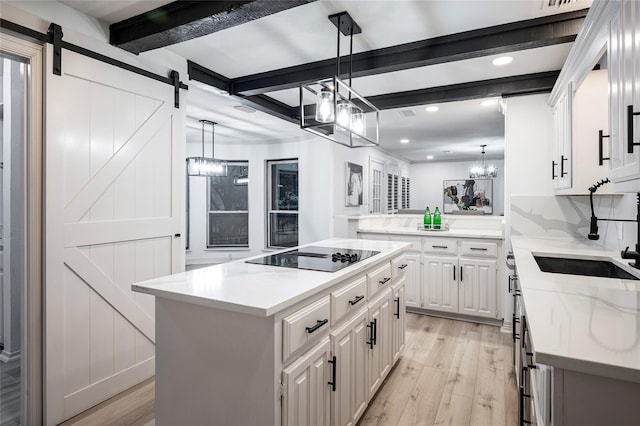 kitchen featuring sink, white cabinetry, a center island, black electric cooktop, and a barn door