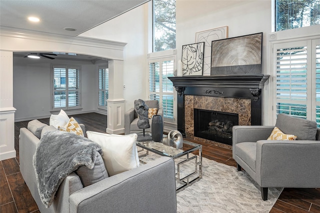 living room featuring ornamental molding, a high end fireplace, hardwood / wood-style floors, and a high ceiling