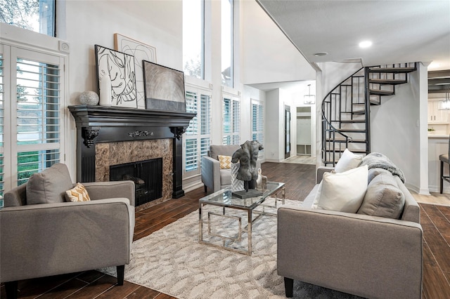 living room featuring a high ceiling, dark wood-type flooring, and a fireplace