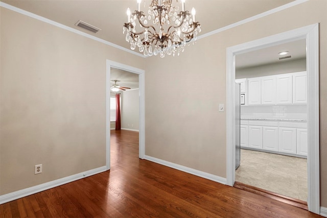 unfurnished dining area featuring ceiling fan with notable chandelier, wood-type flooring, and ornamental molding