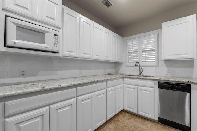 kitchen featuring dishwasher, sink, white microwave, light stone countertops, and white cabinets