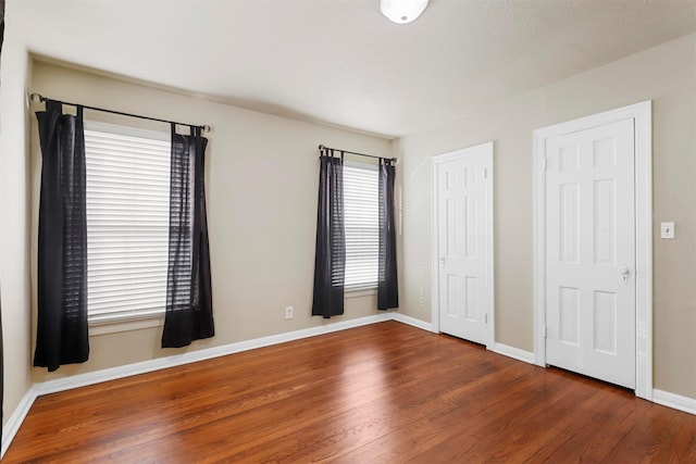 unfurnished bedroom featuring two closets and dark hardwood / wood-style floors