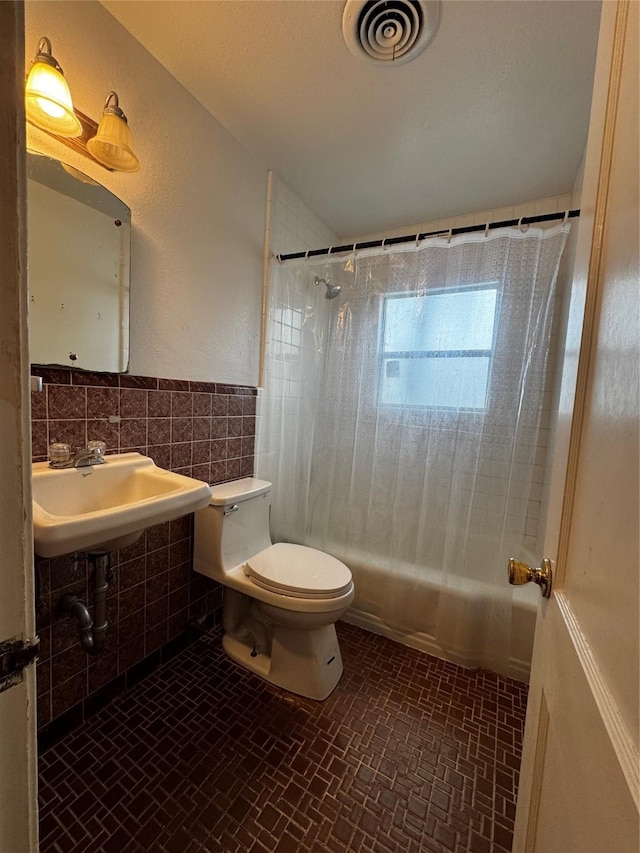 bathroom featuring decorative backsplash, tile walls, toilet, and shower / bath combo with shower curtain