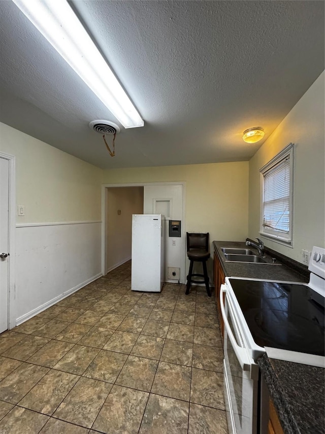 kitchen featuring sink, electric range, and a textured ceiling