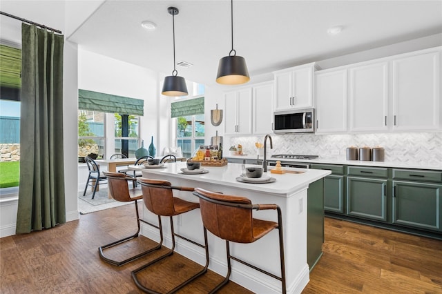 kitchen with green cabinets, white cabinetry, dark hardwood / wood-style floors, an island with sink, and decorative light fixtures