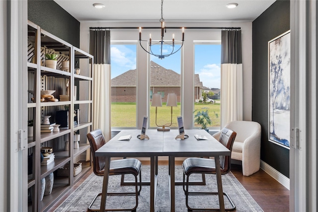 dining space featuring dark wood-type flooring and an inviting chandelier