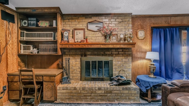 living room featuring a brick fireplace, wood walls, and a textured ceiling