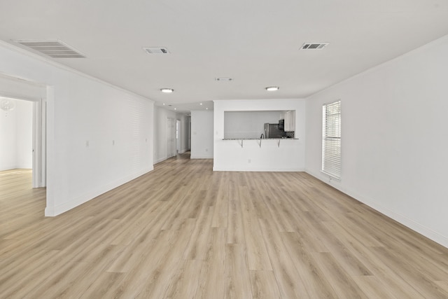 unfurnished living room featuring light wood-type flooring and ornamental molding