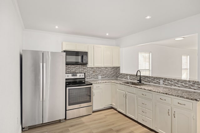 kitchen with white cabinetry, stainless steel appliances, tasteful backsplash, light stone counters, and sink