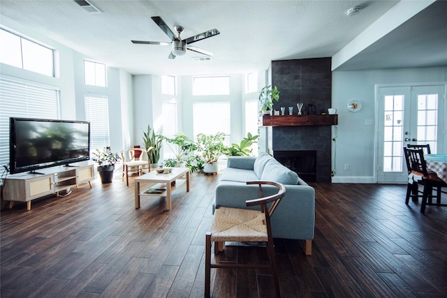 living room featuring ceiling fan, a tile fireplace, dark hardwood / wood-style flooring, and french doors