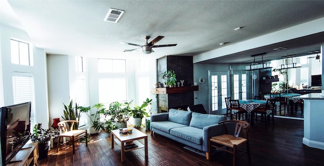 living room with a textured ceiling, dark wood-type flooring, plenty of natural light, and ceiling fan