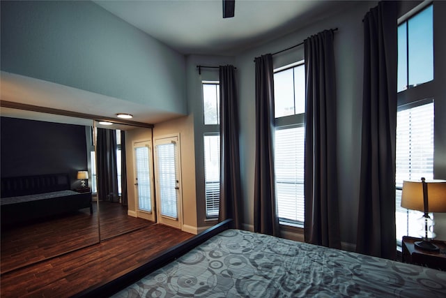 bedroom with ceiling fan, wood-type flooring, a high ceiling, and multiple windows