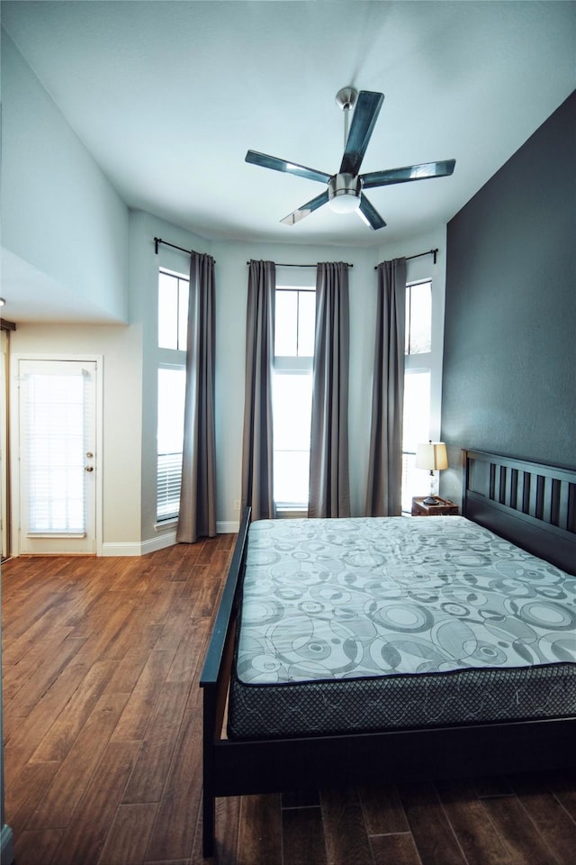 bedroom with ceiling fan, dark hardwood / wood-style flooring, and multiple windows