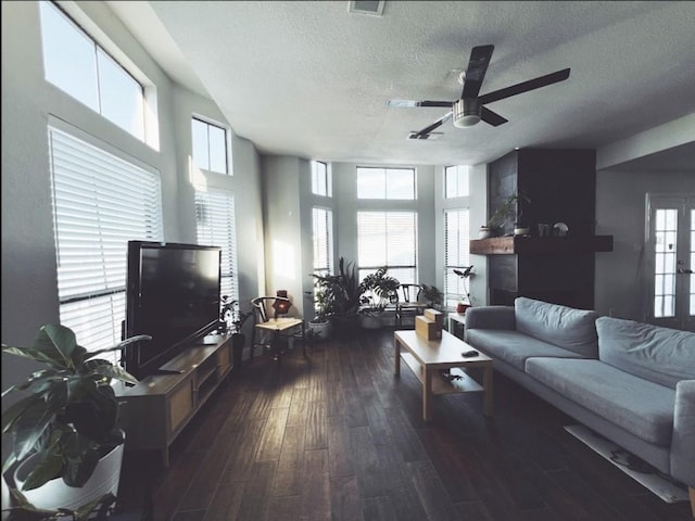 living room featuring ceiling fan, a textured ceiling, dark hardwood / wood-style floors, and a healthy amount of sunlight